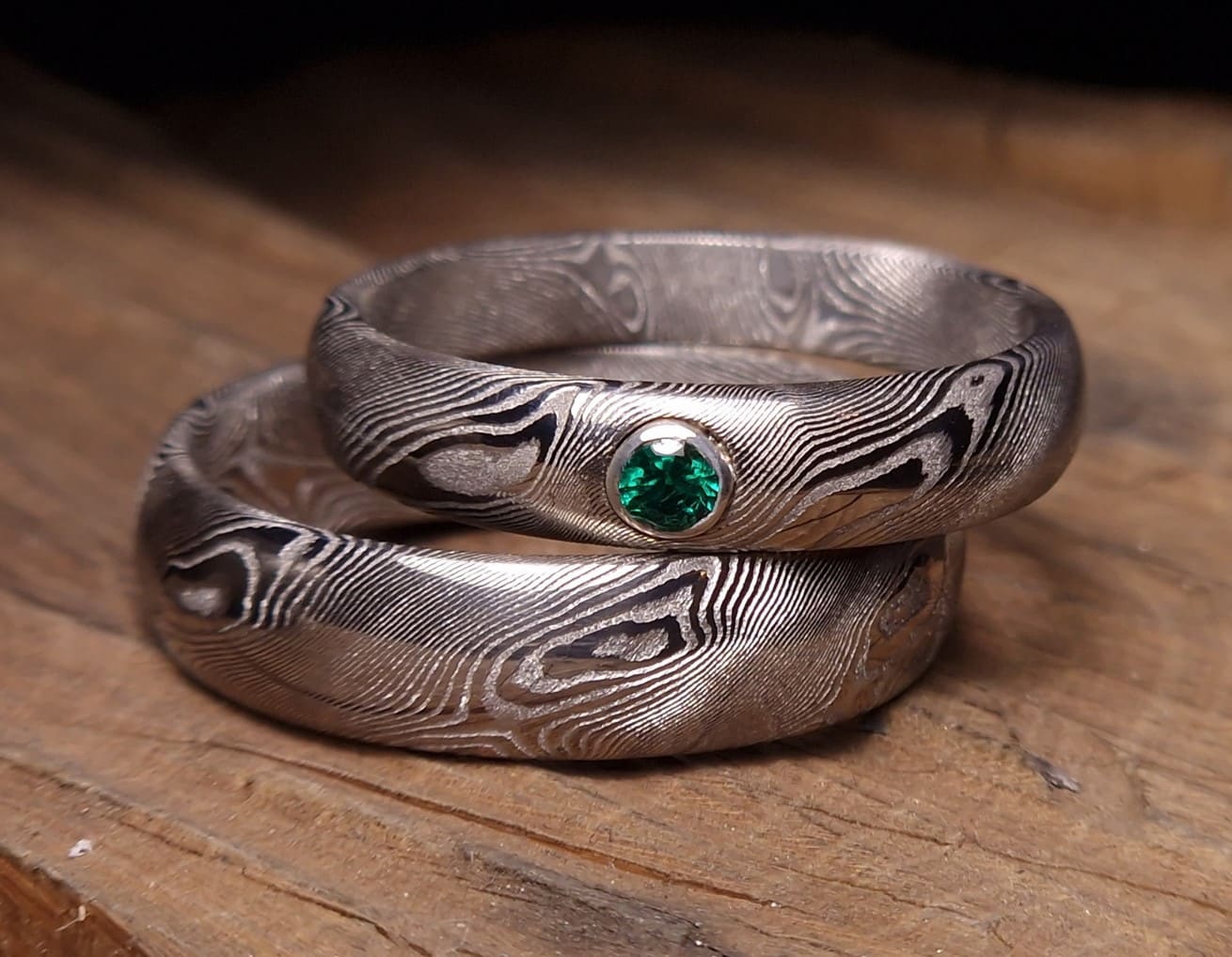 Snubní prsteny z vrstvené oceli damasteel; vzor  napodobuje strukturu dřeva; na každém prstenu je 5-6 "suků". Dámský prsten je osazen přírodním krásně zeleným smaragdem o průměru 2,5 mm,
