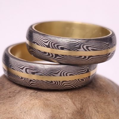 Kované snubní prsteny z vrstvené nerez oceli, doplněné pruhy a vložkováním z 18 karátového zlata(750/1000).